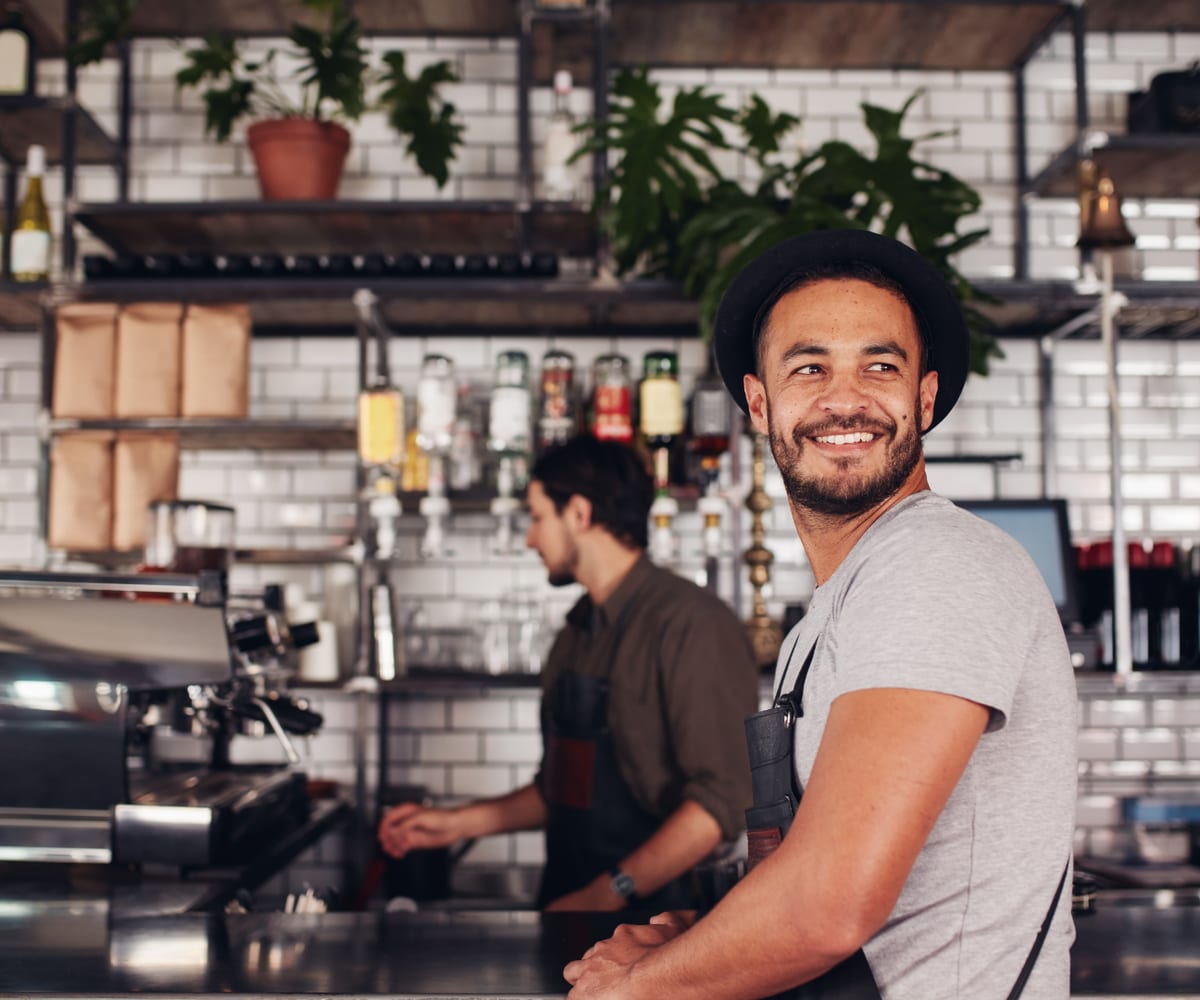 Two people working behind a tiled espresso bar