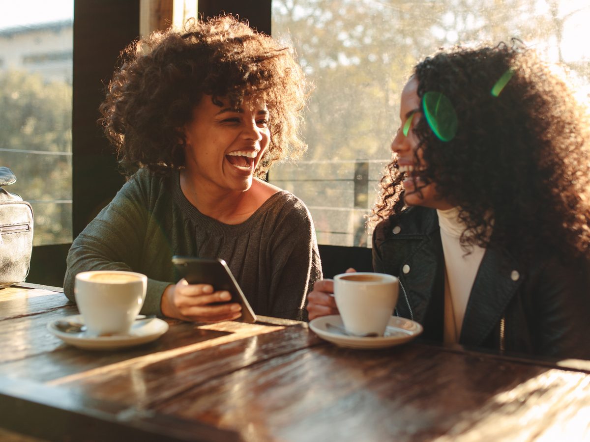 Two people laughing over coffee at a window table