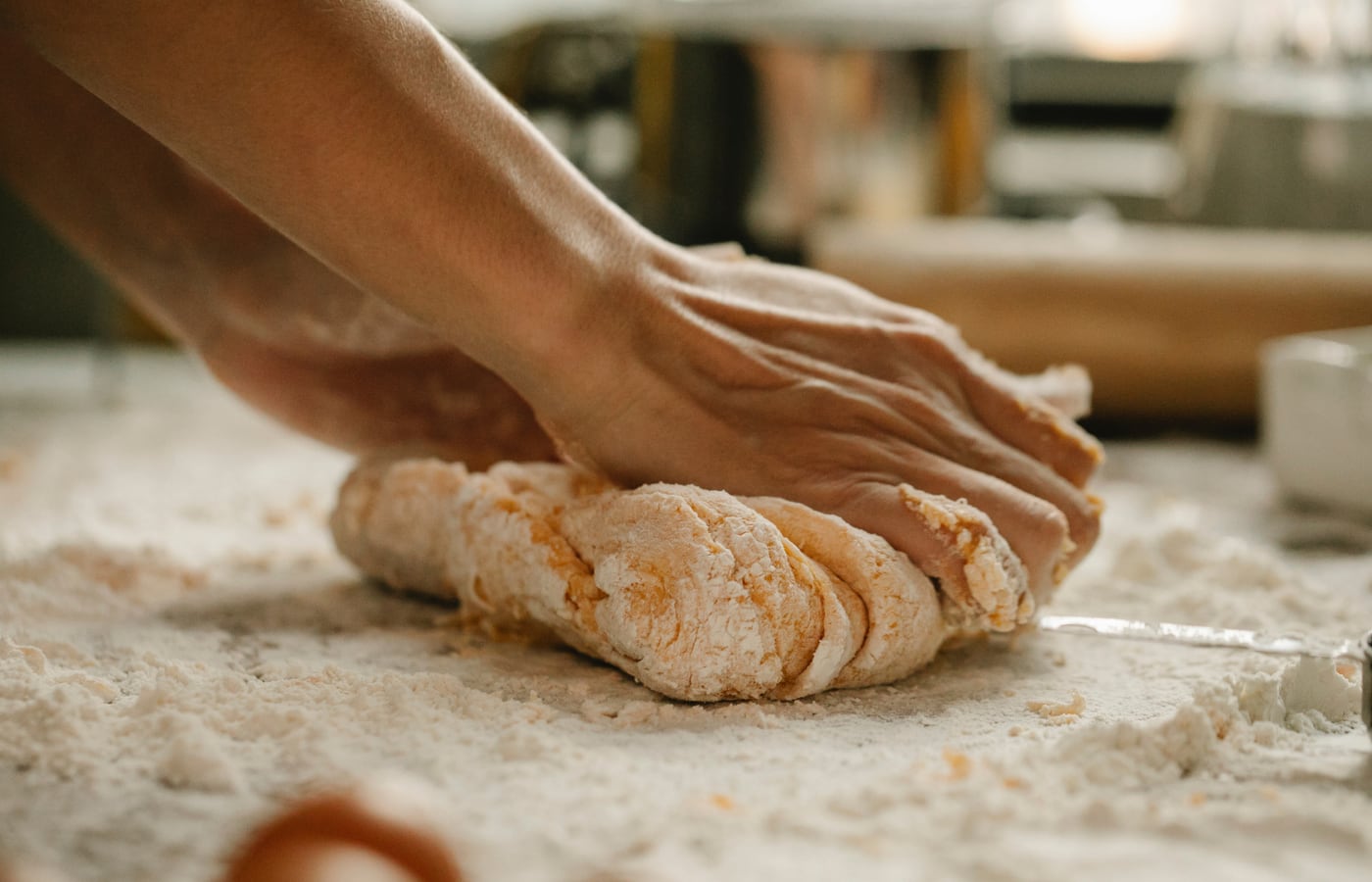 Hands working dough on a floured bench